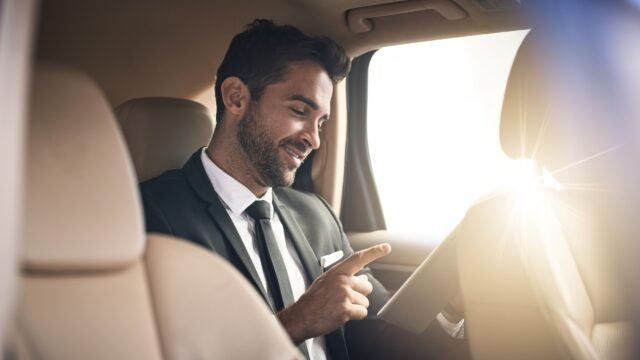 investor checking his phone in the back of a car