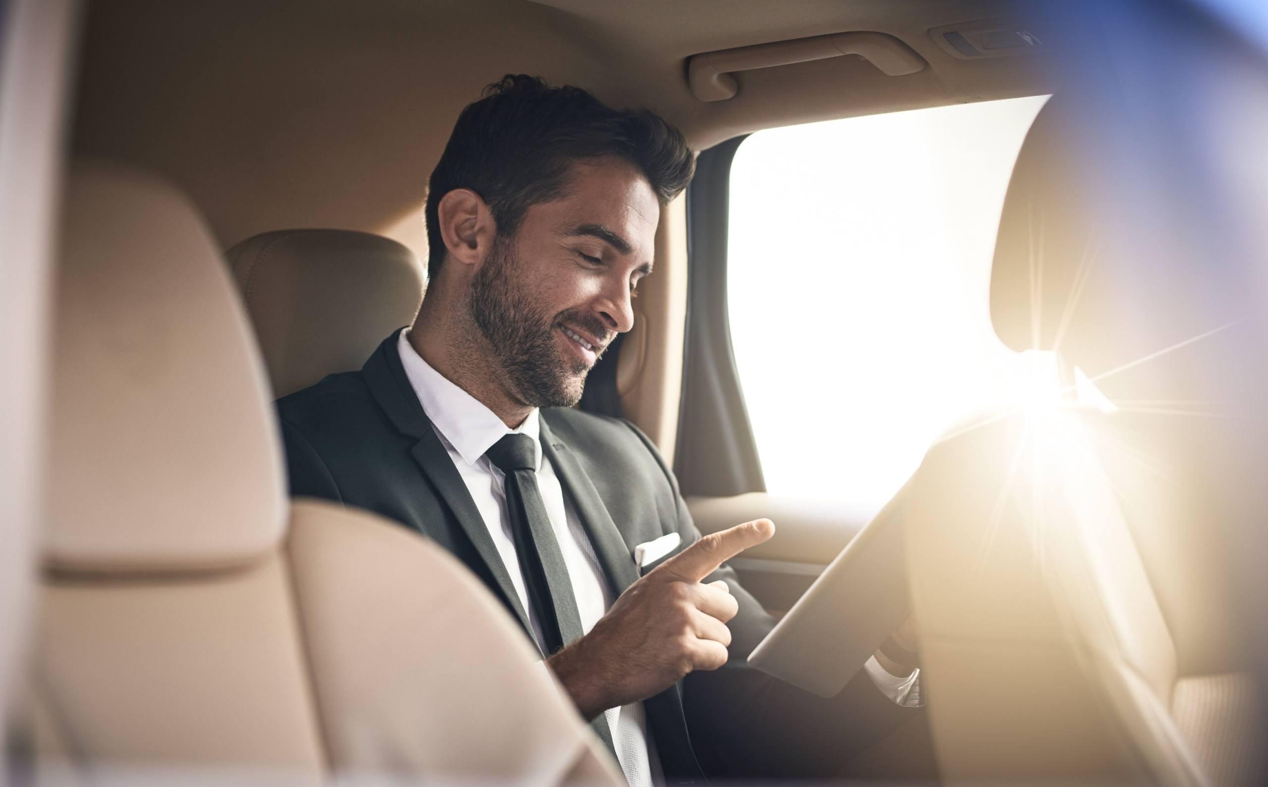 investor checking his phone in the back of a car