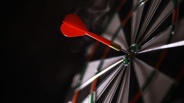 dart hitting bullseye on dart board